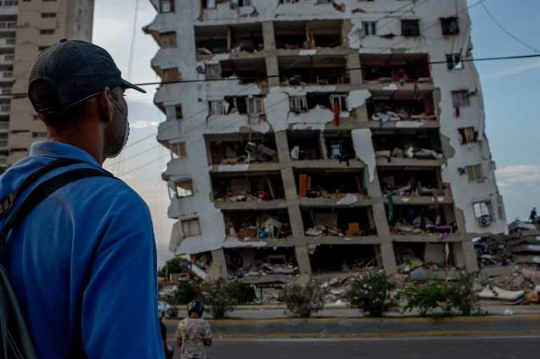 A man watches search efforts for his sister whose ground floor apartment was reduced to rubble in the earthquakes.