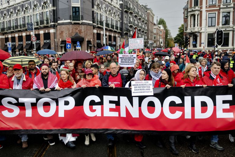Demonstrators including some holding a banner reading "Stop Genocide" take part in a "Red Line" protest demanding "government action to stop the genocide in Gaza" in Amsterdam on October 5, 2025.