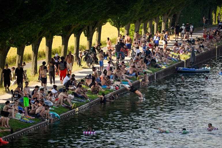 People sit at the side of the Dortmund-Ems Canal in Dortmund, western Germany on June 26, 2026 during a heatwave in Europe.