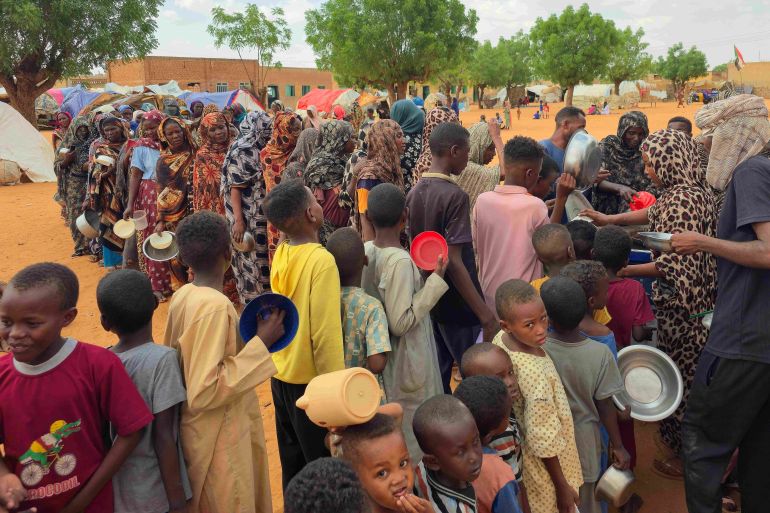 Women and children queue to receive free food being distributed in al-Mohayra camp for displaced people, near the city of El-Obeid in the southern Kordofan region, on June 29, 2026.