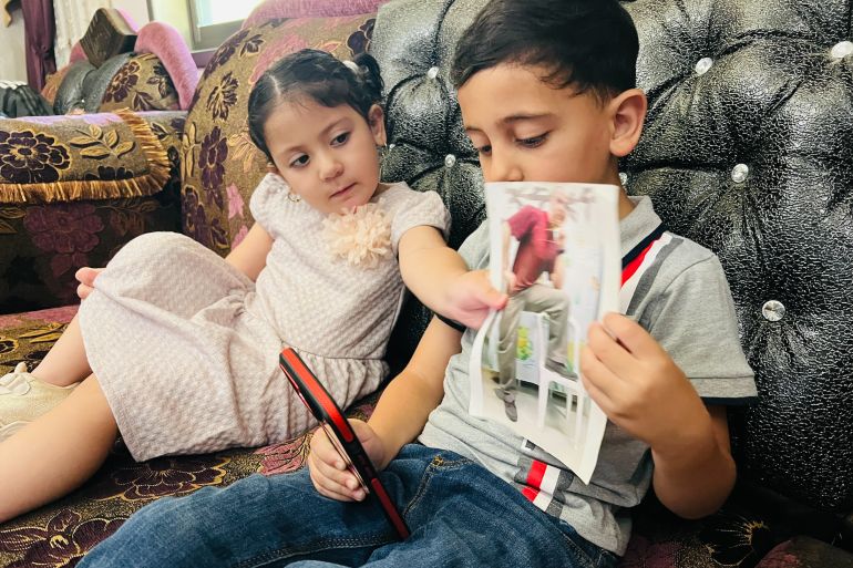 Akram and Julia talk to their father over the phone after being banned from traveling to meet him [Mohamad Turkman/Al Jazeera]
