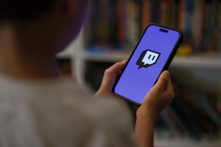 SYDNEY, AUSTRALIA - DECEMBER 07: A 7-year-old teenage boy looks at a phone screen with Twitch logo is displayed on December 07, 2025 in Sydney, Australia. The Online Safety Amendment (Social Media Minimum Age) Act 2024 requires social media platforms, including TikTok, Instagram, Facebook, YouTube, Snapchat, X, Reddit, Threads, Twitch, and Kick to implement age-verification systems and take reasonable steps to prevent account creation by users under 16, with non-compliant platforms facing penalties of up to A$50 million. (Photo by George Chan/Getty Images)