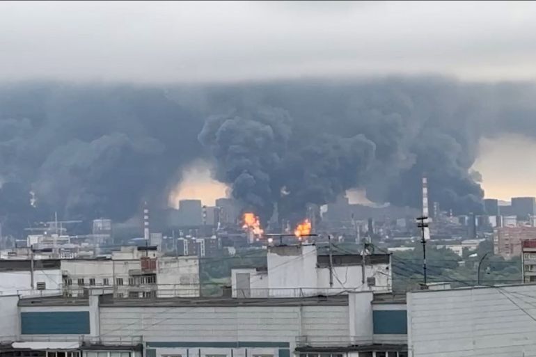 Smoke rises in the distance over a cityscape