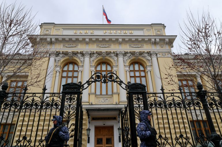 Uniformed Russian National Guard officers stand in a line outside the columned facade of the Central Bank building in Moscow