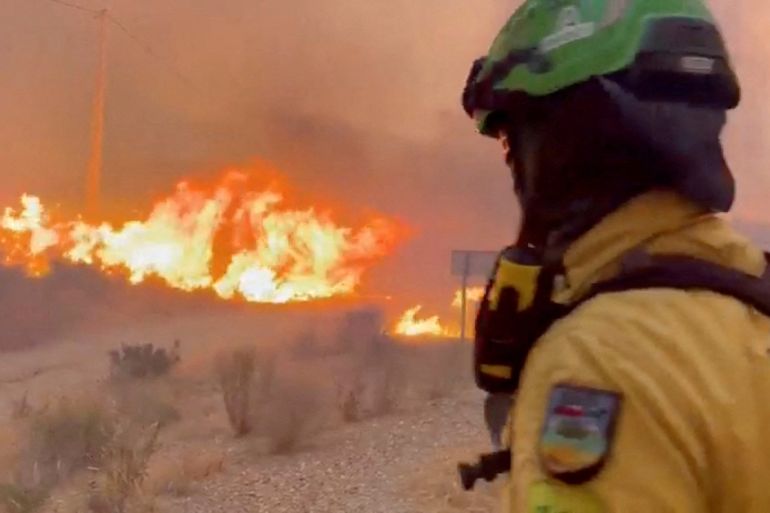 An emergency worker looks on during a wildfire.