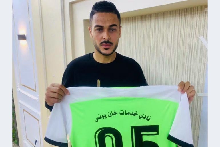 A man holds up a football shirt.